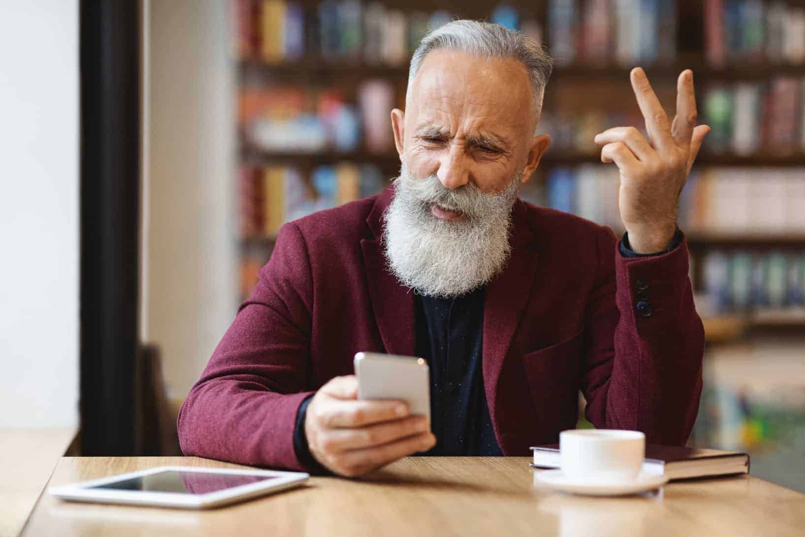frustrated senior man using mobile phone at cafe